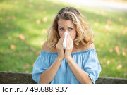 sneezing young girl with nose wiper in a park. Стоковое фото, агентство Ingram Publishing / Фотобанк Лори