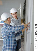 two workers mounting wires in a construction site. Стоковое фото, агентство Ingram Publishing / Фотобанк Лори