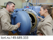 worker talking to female colleague by large steel furnace. Стоковое фото, агентство Ingram Publishing / Фотобанк Лори
