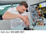 Man working on dismantled electronic device. Стоковое фото, агентство Ingram Publishing / Фотобанк Лори