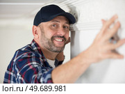 worker fixes the wood molding to the ceiling. Стоковое фото, агентство Ingram Publishing / Фотобанк Лори