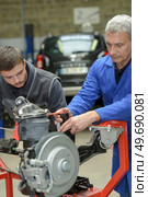 teacher helping students training to be car mechanics. Стоковое фото, агентство Ingram Publishing / Фотобанк Лори