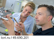 satisfied woman client watching professional plumber for work. Стоковое фото, агентство Ingram Publishing / Фотобанк Лори