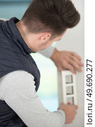 adult electrician man installing plug into a wall. Стоковое фото, агентство Ingram Publishing / Фотобанк Лори