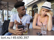 woman annoyed that boyfriend is using smartphone in bar. Стоковое фото, агентство Ingram Publishing / Фотобанк Лори