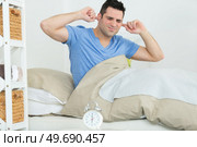man closes his ears by hand from noise of alarm-clock. Стоковое фото, агентство Ingram Publishing / Фотобанк Лори