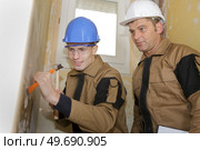 an apprentice scraping the wall. Стоковое фото, агентство Ingram Publishing / Фотобанк Лори