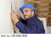 portrait of professional man stripping wallpaper with scraper. Стоковое фото, агентство Ingram Publishing / Фотобанк Лори