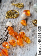  orange glass beads around old style wooden background. close up. hobby and hand made concept. Стоковое фото, агентство Ingram Publishing / Фотобанк Лори