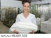 happy young female employee carrying laundry basket in laundromat. Стоковое фото, агентство Ingram Publishing / Фотобанк Лори