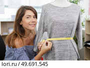 beautiful young woman in eyeglasses measuring dummy with tape. Стоковое фото, агентство Ingram Publishing / Фотобанк Лори