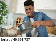 happy young man with apron cooking pasta. Стоковое фото, агентство Ingram Publishing / Фотобанк Лори