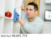 man cleaning dust from bookshelf. Стоковое фото, агентство Ingram Publishing / Фотобанк Лори