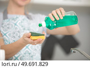 woman pouring washing up liquid on to a sponge. Стоковое фото, агентство Ingram Publishing / Фотобанк Лори