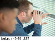young man looks out the window with binoculars close-up. Стоковое фото, агентство Ingram Publishing / Фотобанк Лори