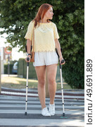disabled young woman walking on crutches in street. Стоковое фото, агентство Ingram Publishing / Фотобанк Лори