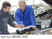 student with instructor repairing a car during apprenticeship. Стоковое фото, агентство Ingram Publishing / Фотобанк Лори