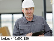 portrait of mature male worker wearing overalls holding digital tablet. Стоковое фото, агентство Ingram Publishing / Фотобанк Лори