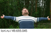 Young man stands with her arms outstretched to the side in the green park. Feeling free outdoor. Winning life achievement, freedom goal concept. Guy business employer, manager inspired in nature. Стоковое видео, видеограф Марина Демидюк / Фотобанк Лори