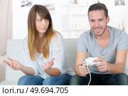 annoyed girlfriend waiting for boyfriend to stop playing video-games. Стоковое фото, агентство Ingram Publishing / Фотобанк Лори