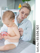 female paediatrician holding stethoscope on infants back. Стоковое фото, агентство Ingram Publishing / Фотобанк Лори