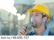 a builder smokes an e cigarette. Стоковое фото, агентство Ingram Publishing / Фотобанк Лори