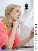contemplative fashion designer looking at sketch. Стоковое фото, агентство Ingram Publishing / Фотобанк Лори