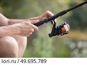 hands fisherman keep spinning rod. Стоковое фото, агентство Ingram Publishing / Фотобанк Лори