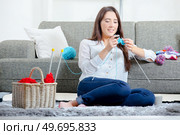 Young girl sat on floor knitting. Стоковое фото, агентство Ingram Publishing / Фотобанк Лори