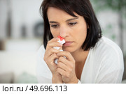 woman with nosebleed sitting in living room. Стоковое фото, агентство Ingram Publishing / Фотобанк Лори
