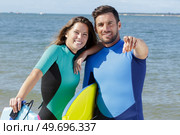 surfers couple pointing at the camera. Стоковое фото, агентство Ingram Publishing / Фотобанк Лори