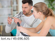 personal trainer helping his female client on elliptical machine. Стоковое фото, агентство Ingram Publishing / Фотобанк Лори