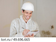 builder laughing as he writes on clipboard. Стоковое фото, агентство Ingram Publishing / Фотобанк Лори