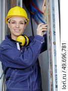female electrician measuring space for installing fuseboard. Стоковое фото, агентство Ingram Publishing / Фотобанк Лори
