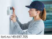 Woman fitting electronic keypad to wall. Стоковое фото, агентство Ingram Publishing / Фотобанк Лори