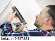 handyman applying sealant with a gun. Стоковое фото, агентство Ingram Publishing / Фотобанк Лори