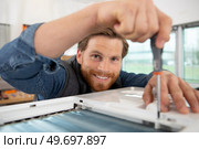 a happy worker screwing a window. Стоковое фото, агентство Ingram Publishing / Фотобанк Лори