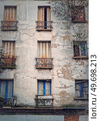 Abandoned building facade. Trees and bushes growing out of windows, rusted louvers and cracked concrete walls. Стоковое фото, агентство Ingram Publishing / Фотобанк Лори