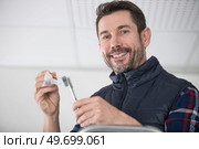 happy man on ladder attaching lamp. Стоковое фото, агентство Ingram Publishing / Фотобанк Лори
