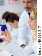 Science student looking at liquid in erlenmeyer flask. Стоковое фото, агентство Ingram Publishing / Фотобанк Лори