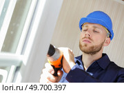 handyman using a cordless screwdriver to install a window. Стоковое фото, агентство Ingram Publishing / Фотобанк Лори