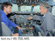 Engineer talking to trainee in cockpit of aircraft. Стоковое фото, агентство Ingram Publishing / Фотобанк Лори