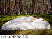 Woman sleeps on a mattress in the summer forest. The girl is resting in nature. Стоковое фото, агентство Ingram Publishing / Фотобанк Лори