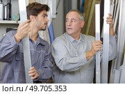 construction workers lifting reinforcement rods at a factory. Стоковое фото, агентство Ingram Publishing / Фотобанк Лори