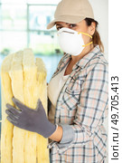 female worker in protective gloves holding insulating rock wool insulation. Стоковое фото, агентство Ingram Publishing / Фотобанк Лори