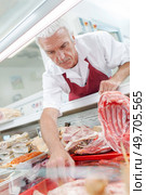 butcher picking a piece of meat. Стоковое фото, агентство Ingram Publishing / Фотобанк Лори