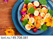 Salad of fresh fruits and nasturtium leaves on the old wooden table. Flat lay.. Vegetarian fruit salad with nasturtium. Стоковое фото, агентство Ingram Publishing / Фотобанк Лори