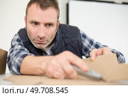 male worker scoring cardboard with craft knife. Стоковое фото, агентство Ingram Publishing / Фотобанк Лори