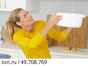 woman collecting leaking water in bucket. Стоковое фото, агентство Ingram Publishing / Фотобанк Лори