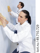 young woman is hand sanding wall. Стоковое фото, агентство Ingram Publishing / Фотобанк Лори